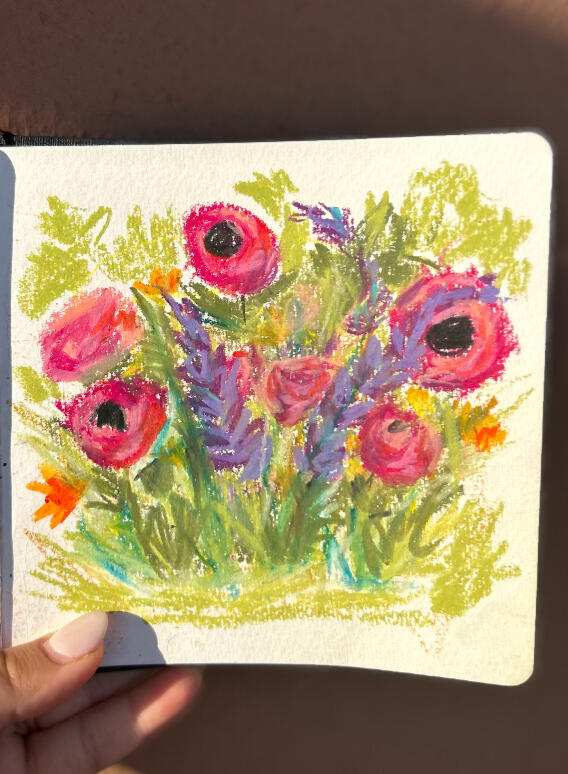 meadow on sketchbook hand holding sketchbook to show a pastel painting of a meadow with semi abstract wild flowers on green background