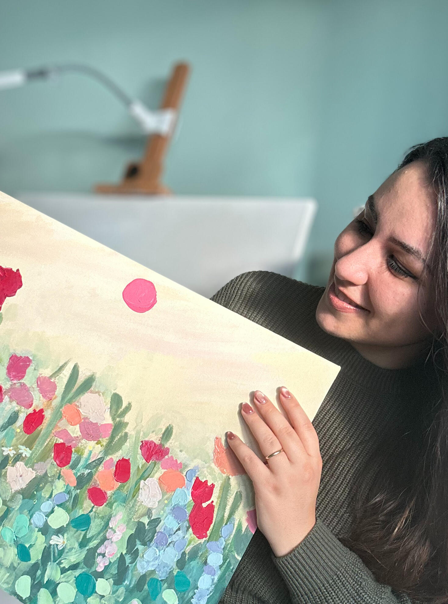 Artist holding floral painting artist Giulia holding a floral textured painting on canvas panel
